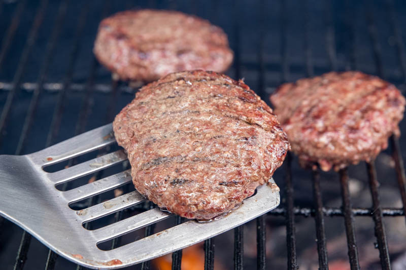 The Step-By-Step Grilling Method - Brioche Burgers On Charcoal - Placing Grilling Beef Burgers With A Spatula